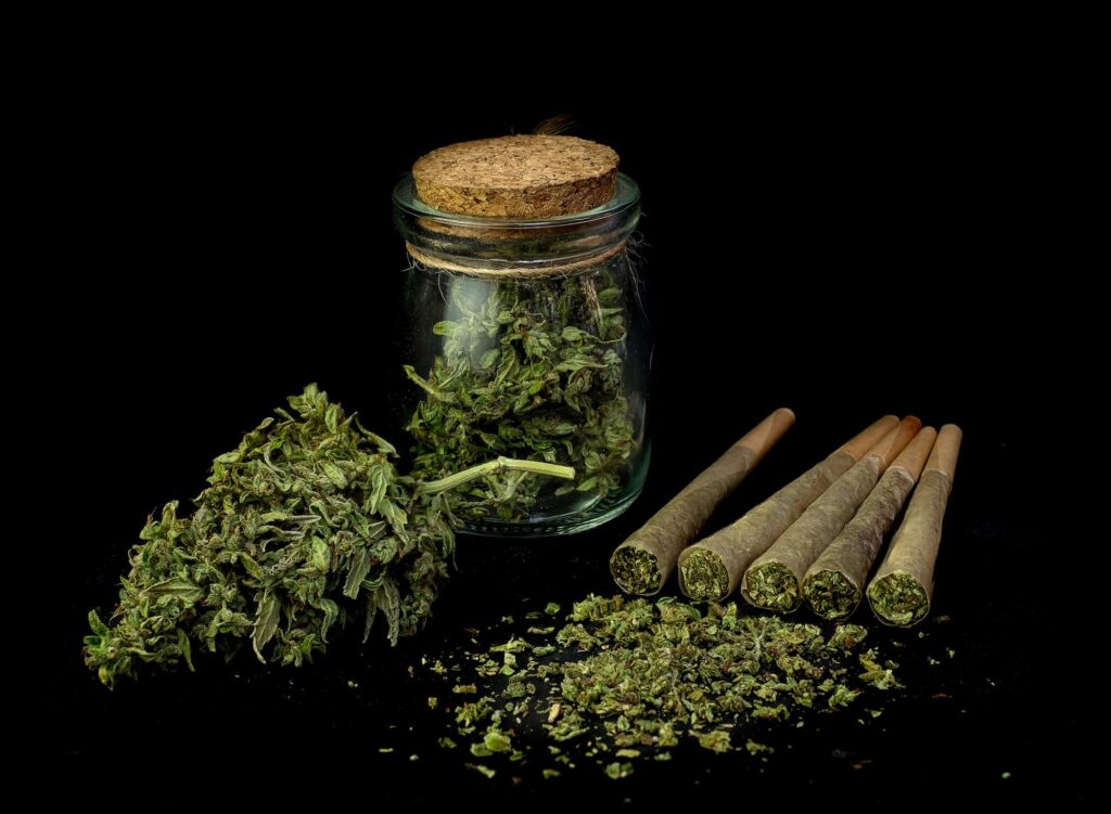 a jar of marijuana next to freshly rolled pre-rolls